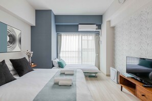 A modern hotel room with a large bed, a TV, and a window with curtains.