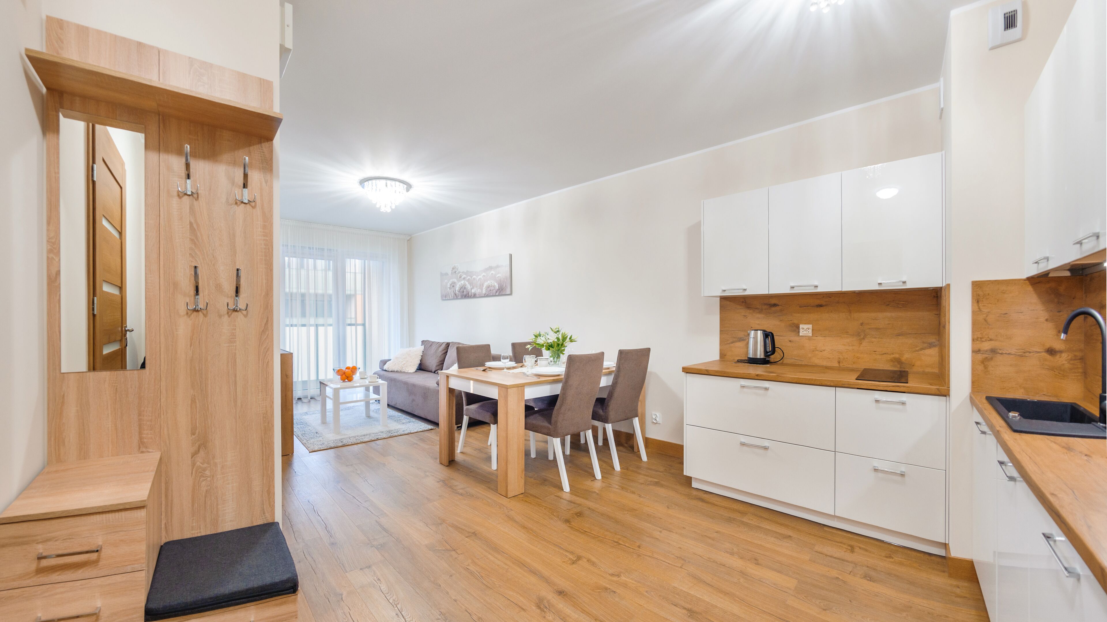 A modern apartment with a dining area, kitchen, and a staircase.
