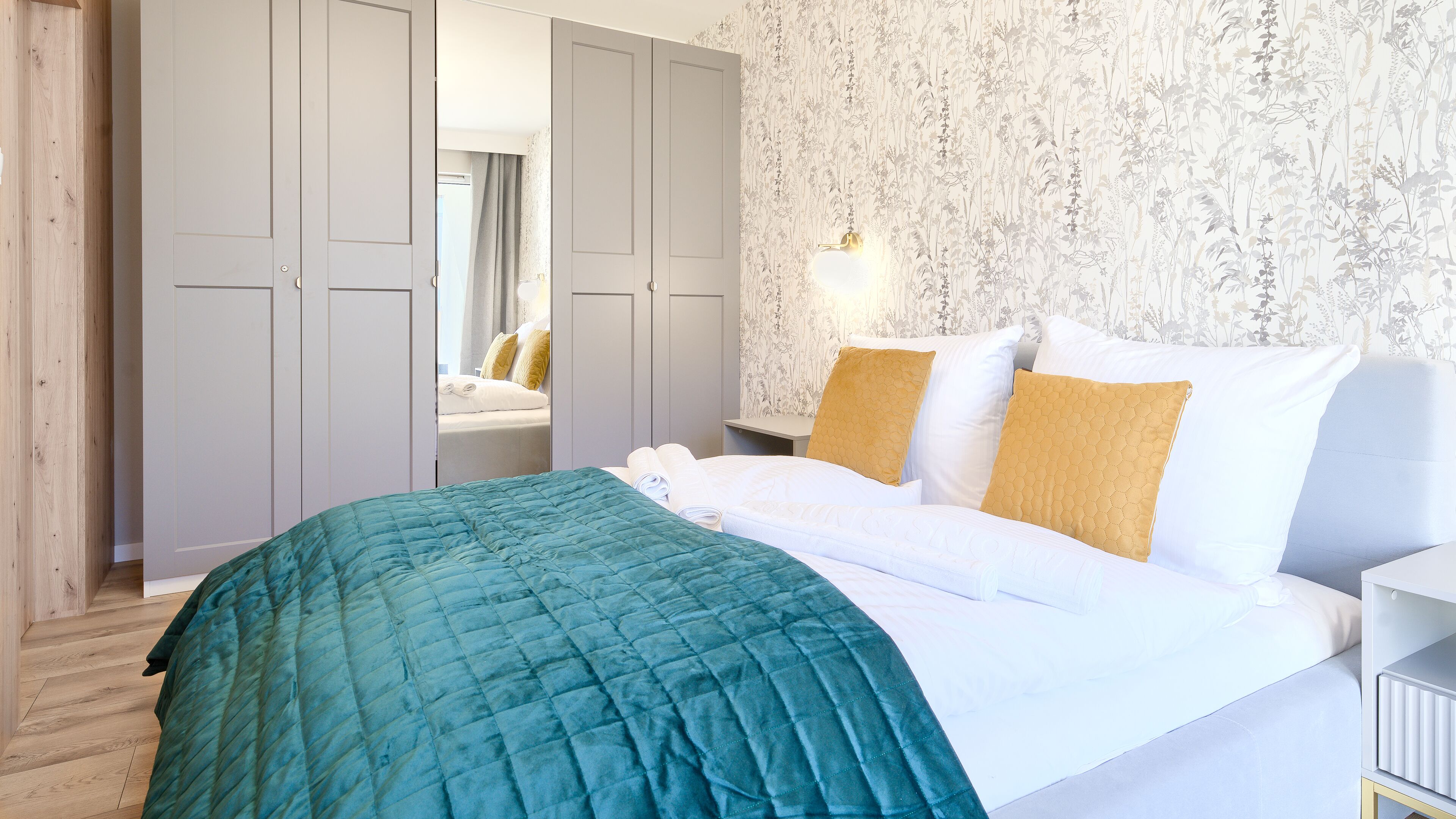 Een slaapkamer met een bed, nachtkastje, spiegel en kledingkast.
