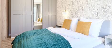 Een slaapkamer met een bed, nachtkastje, spiegel en kledingkast.