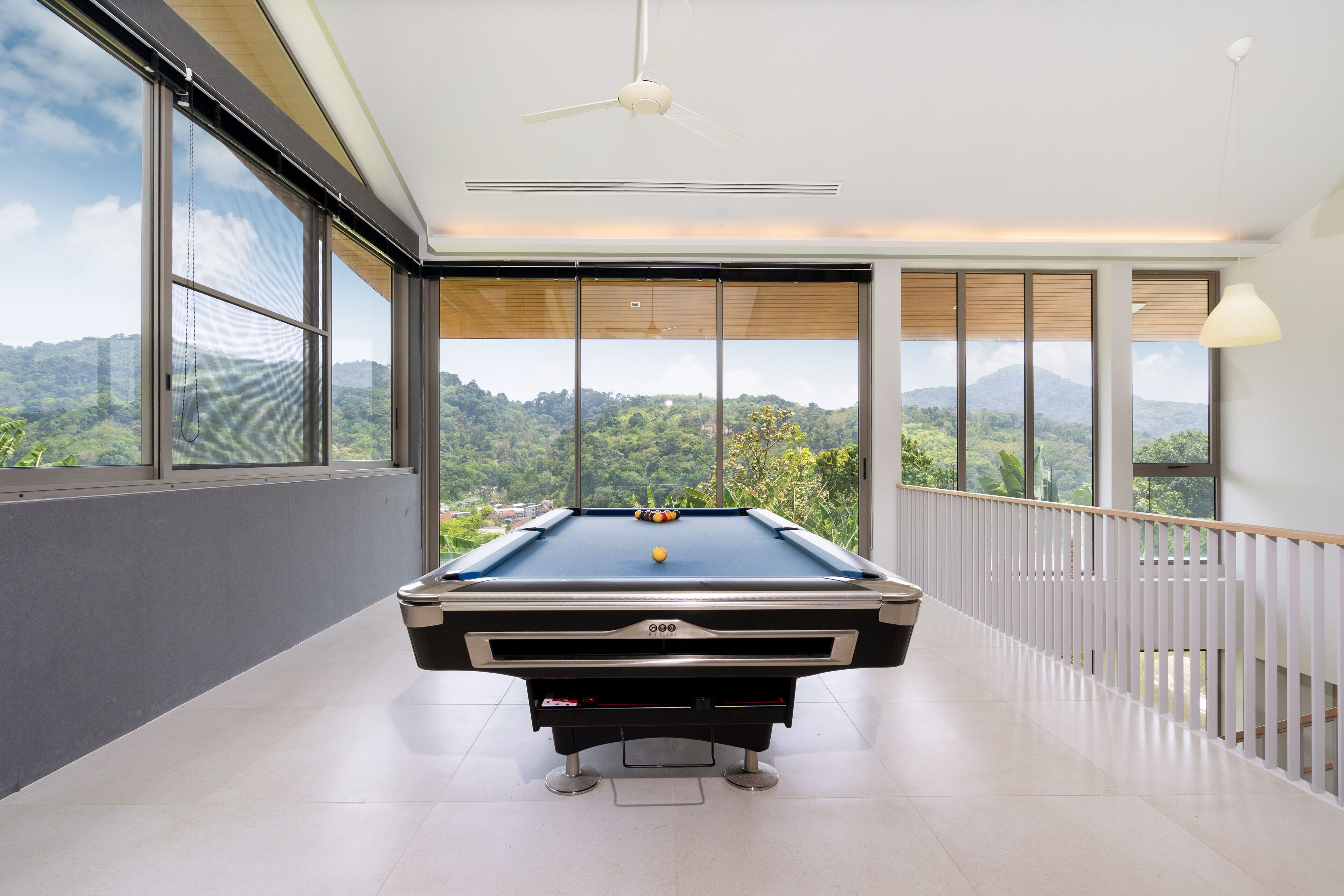 Una mesa de billar en una sala amplia con ventanas grandes que dan a un paisaje montañoso.