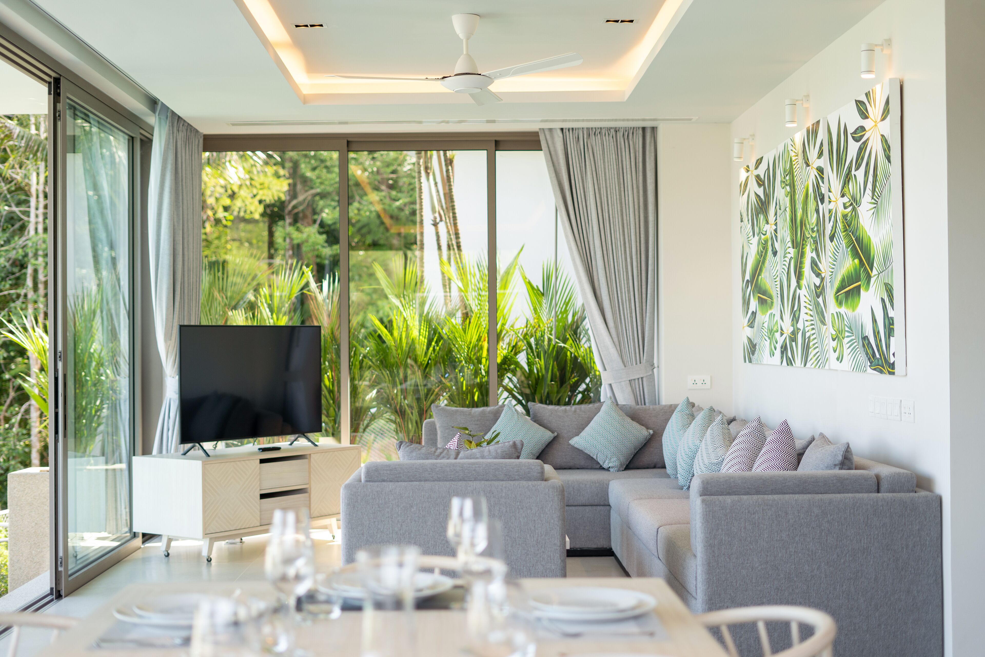 A modern living room with a sofa, TV, and dining area.
