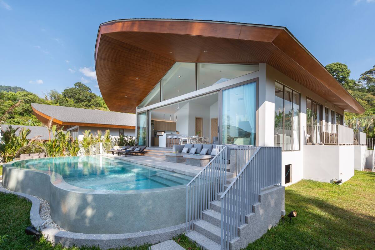 A modern house with a swimming pool, large glass windows, and a wooden roof.