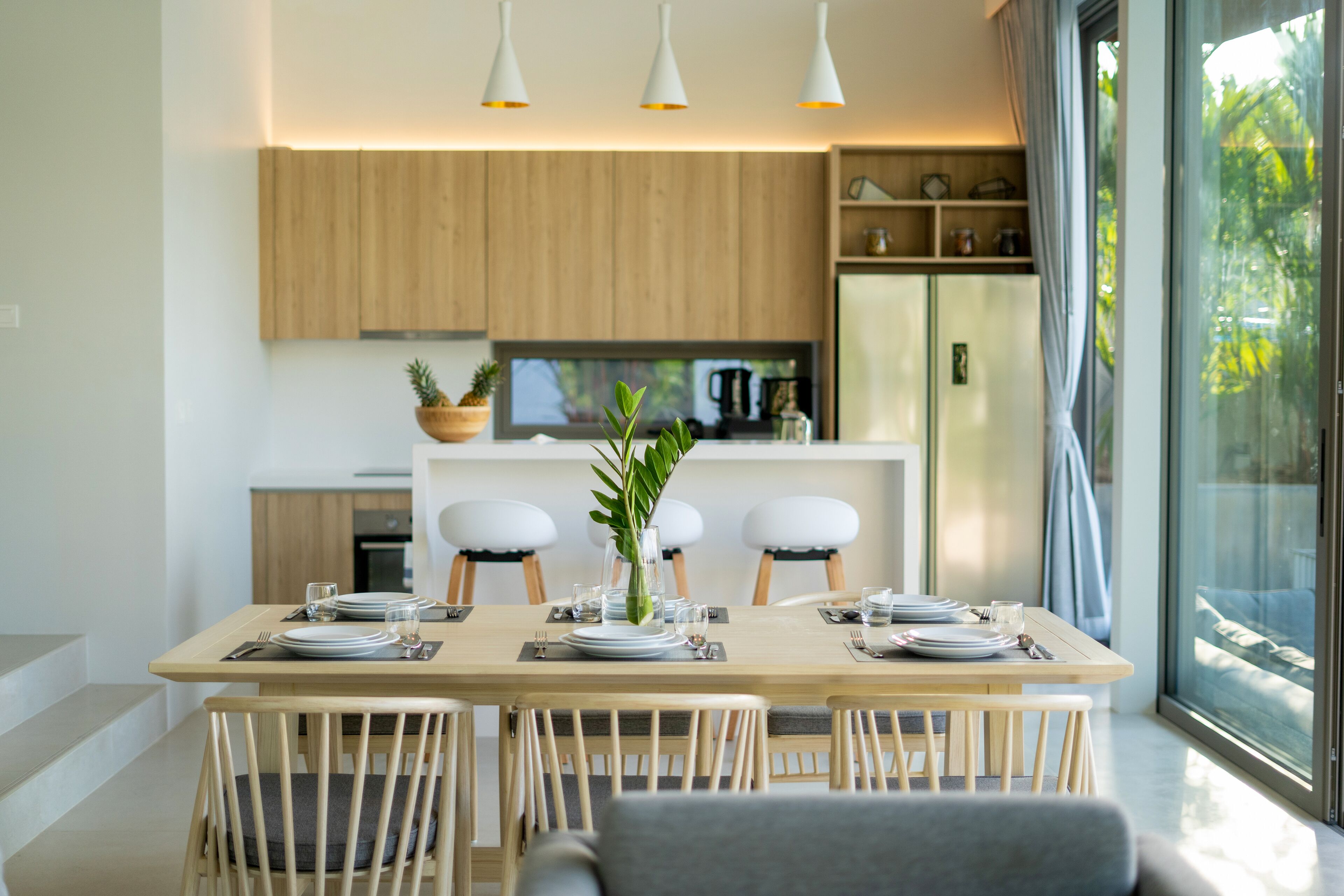 A modern dining area with a wooden table set for four, surrounded by wooden chairs.