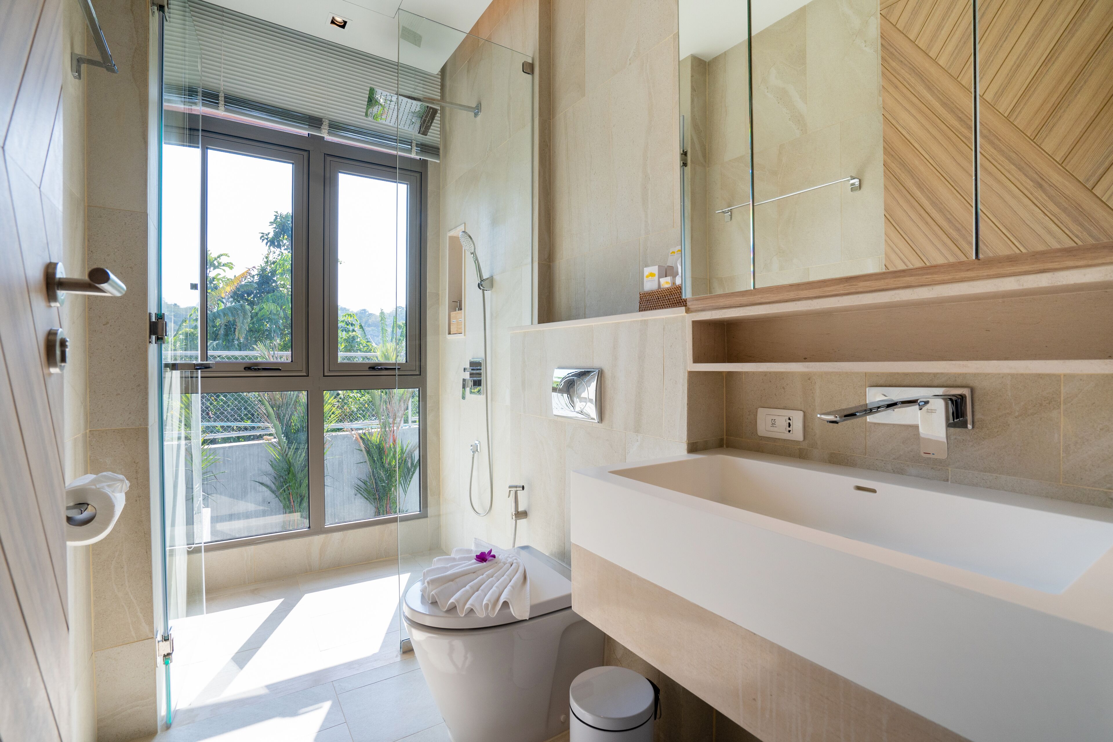 Un baño moderno con cabina de ducha de vidrio, un lavabo blanco y un espejo grande.