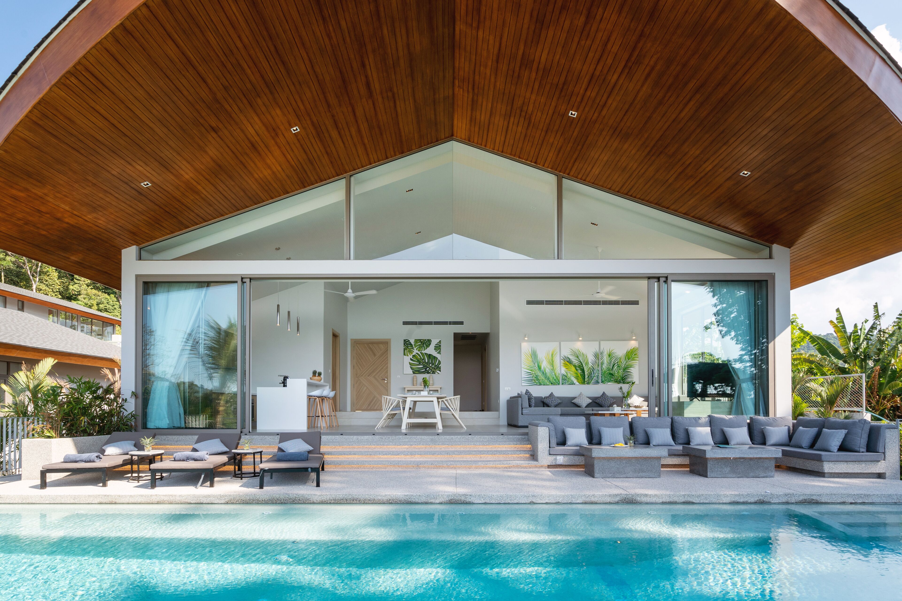 Una casa moderna con piscina, amplios ventanales de vidrio y un espacio exterior cubierto.