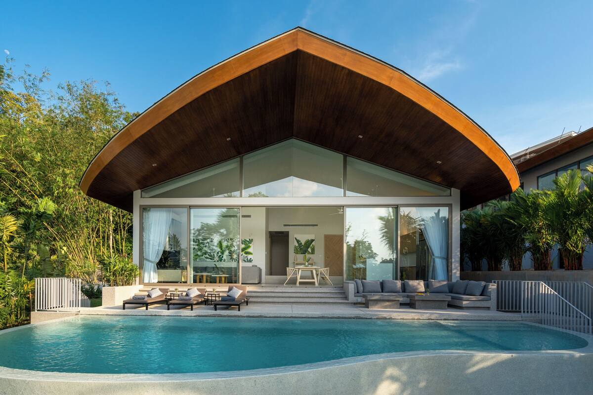 A modern house with a large pool, glass doors, and a covered patio area.