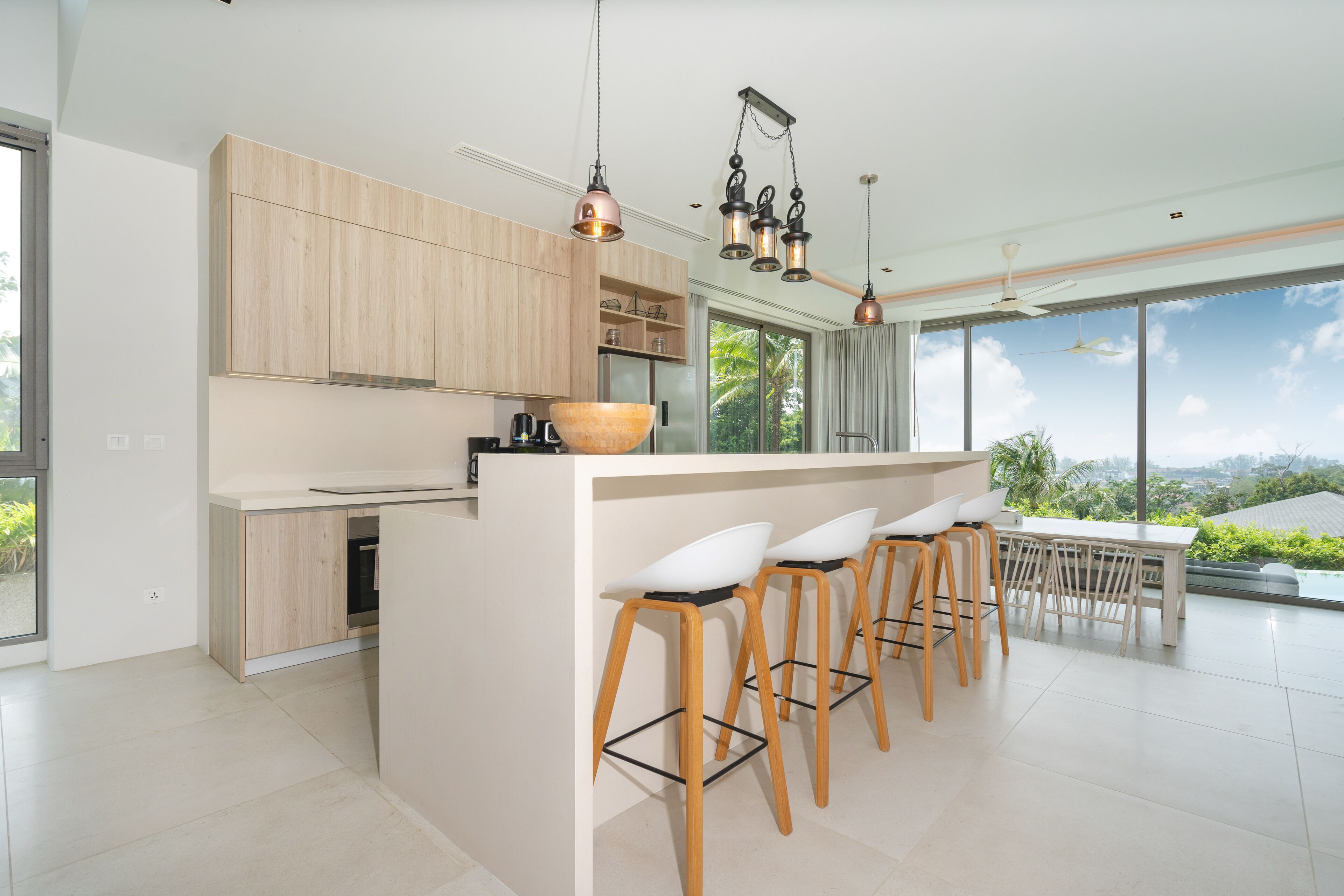 A modern kitchen with wooden cabinets, a large island with bar stools, and pendant lighting.