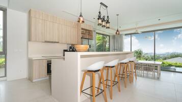 A modern kitchen with wooden cabinets, a large island with bar stools, and pendant lighting.