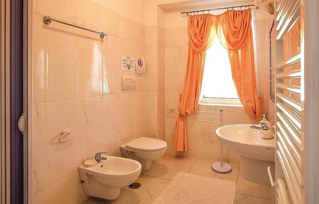 Une salle de bain avec deux toilettes, un bidet, un lavabo et un espace douche.