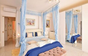 Une chambre à coucher avec un lit à baldaquin, un grand miroir et une table de chevet.