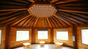 A cabin with a hexagonal skylight, wooden walls, and large windows.