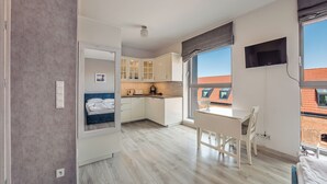 A compact apartment with a kitchenette, a dining area, and a bedroom with a large window.
