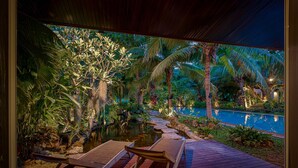 A wooden deck with two lounge chairs overlooking a swimming pool surrounded by tropical vegetation. - 6BR Luxury Tropical Pool Villa PH125 (Cha-am)