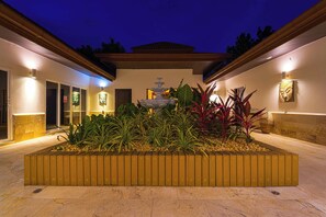 A courtyard with a fountain, surrounded by plants and a wooden planter. - 6BR Luxury Tropical Pool Villa PH125 (Cha-am)