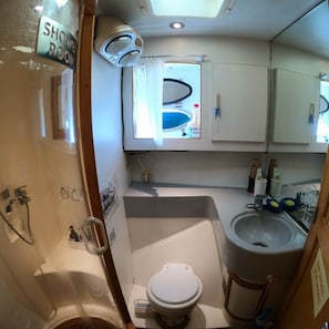 A compact bathroom with a shower, toilet, sink, and mirror. - Yacht King (Busan)