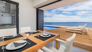 A dining area with a view of the sea, a pool, and outdoor seating. - Lovely home in Kosljun (Kosljun)