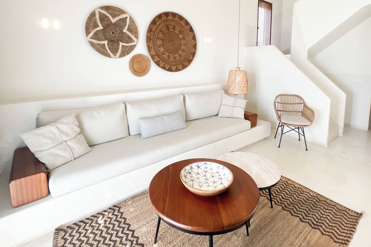 A modern living room with a white sofa, a round wooden coffee table, and a ceiling fan.