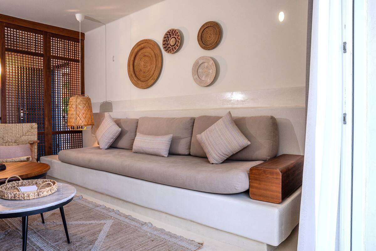 A modern living room with a sofa, wall-mounted woven baskets, and a small round table.