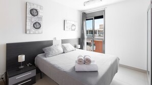 Ein modernes Schlafzimmer mit Bett, Nachttisch und Kunstwerk an der Wand.