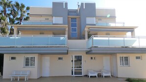 A modern two-story building with a swimming pool, outdoor seating, and a balcony.
