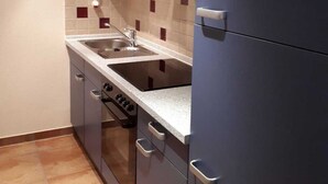 A compact kitchen with a double sink, a stove, and a refrigerator. - Apartment on Gregoriusberg Object-ID 121158 (Waren (Müritz))