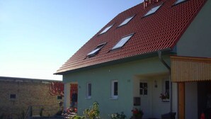A two-story house with a red-tiled roof, a front porch, and a small garden. - Apartment on Gregoriusberg Object-ID 121158 (Waren (Müritz))