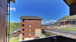 A wooden building with a balcony, a stone pathway, and a mountainous backdrop. - Lovely studio cabin for 4 people, near slopes (Belle Plagne)