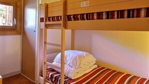 A bunk bed room with a window, a door, and a striped bedspread. - Lovely studio cabin for 4 people, near slopes (Belle Plagne)