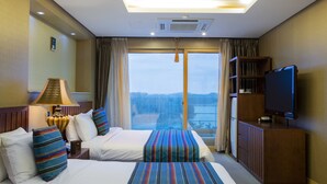 A hotel room with two beds, a television, a bookshelf, and a large window with a view.