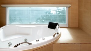 A modern bathroom with a freestanding bathtub, a window with a view, and wooden flooring.