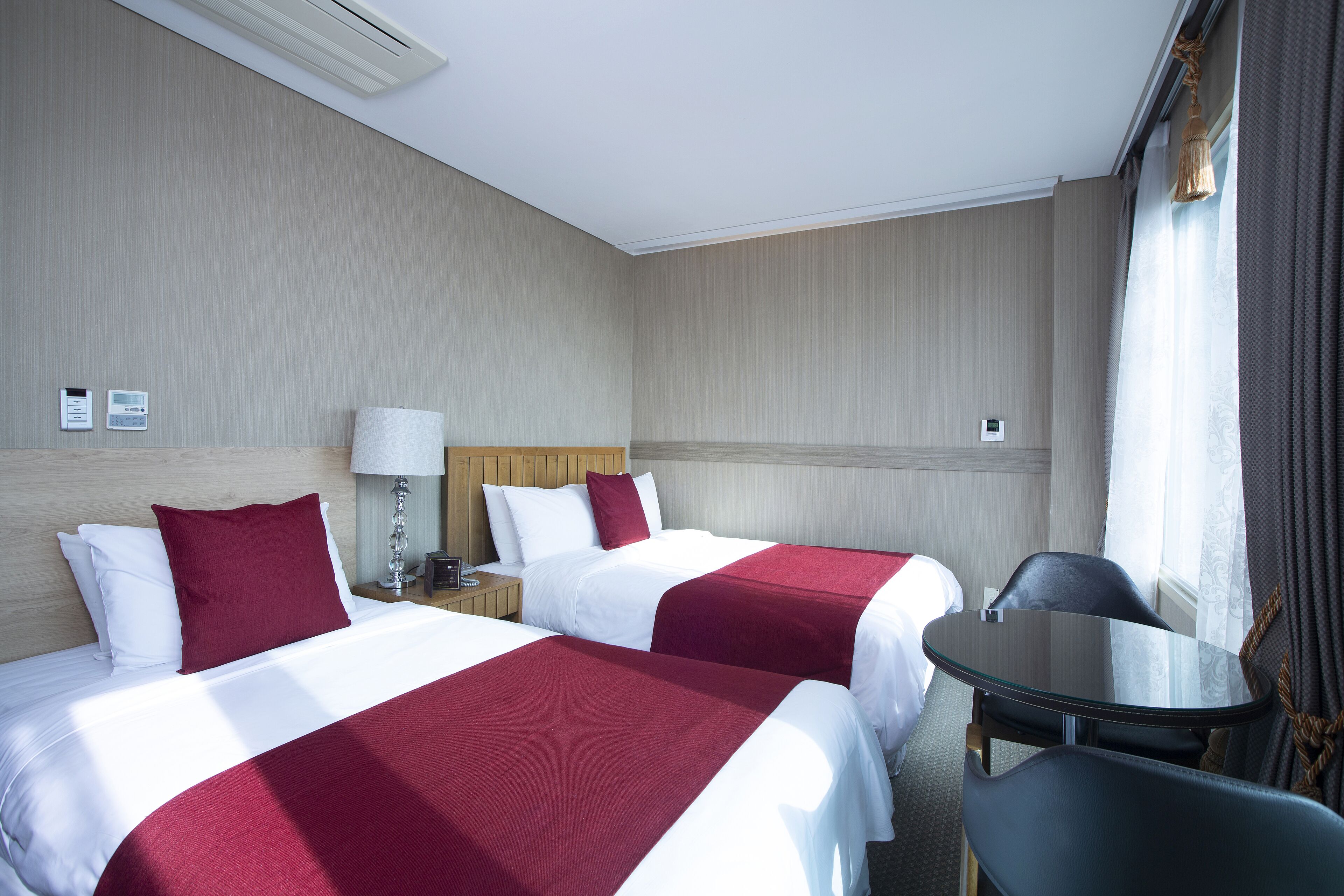 A hotel room with two beds, a small table, and a chair.