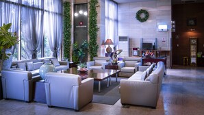 A modern hotel lobby with a seating area, a reception desk, and a television. - Ritz Plaza Hotel (Gunsan)