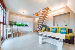 A modern living room with a staircase, a dining area, and a kitchen. - Apartamenty Sun & Snow Willa Hania (Krynica Morska)