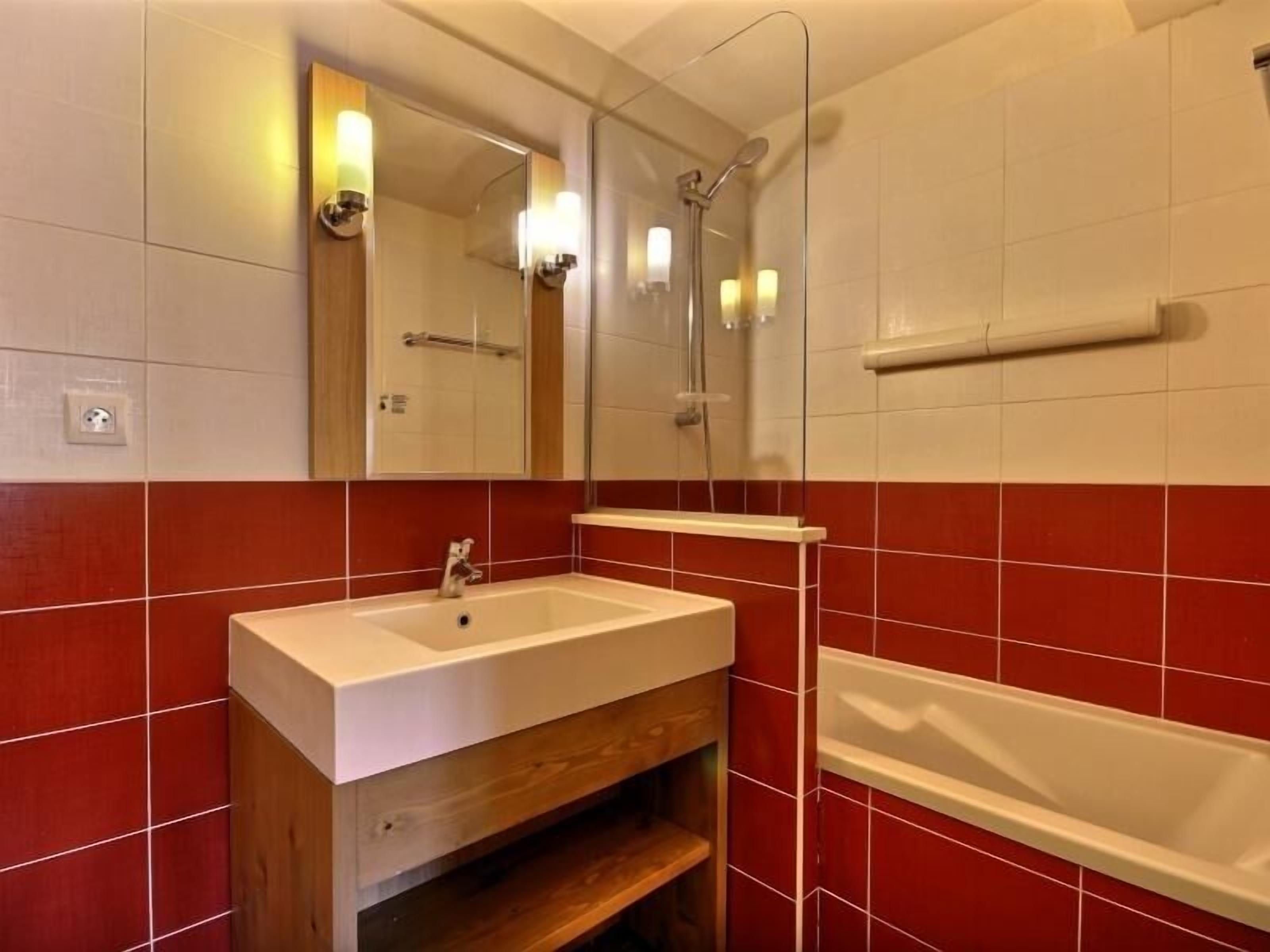 A bathroom with a sink, mirror, and shower.