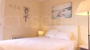 A bedroom with a bed, a nightstand, a lamp, and a wall-mounted sign.