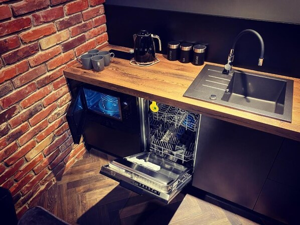 A compact kitchen with a dishwasher, a sink, and a coffee maker. - Old Town Luxury Apartments Zgorzelec (Zgorzelec)