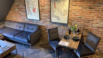 Un interior moderno con pared de ladrillo, un sofá, una mesa de comedor con sillas y obras de arte.
