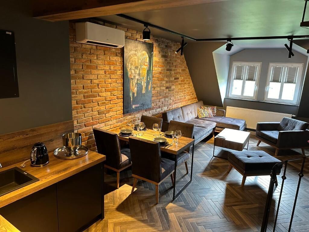 Un espacio habitable moderno estilo loft con zona de comedor, cama en un entrepiso y un amplio ventanal que proporciona luz natural.
