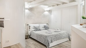 A modern bedroom with a bed, white walls, a wooden ceiling, and a large mirror. - Enchanting studio apartment in Trastevere (Roma)