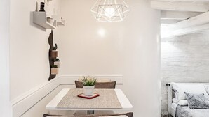 A modern dining area with a white table, a geometric pendant light, and a small plant on the table. - Enchanting studio apartment in Trastevere (Roma)