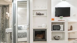 A modern bathroom with a glass shower enclosure, a white sink, and a bed with a leaf-patterned bedspread. - Enchanting studio apartment in Trastevere (Roma)