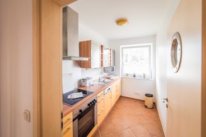 Une cuisine de taille réduite, dotée de meubles en bois, d’un four à micro-ondes, d’un grille-pain et d’un évier.