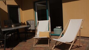 A patio with two white lounge chairs, a table, and chairs.