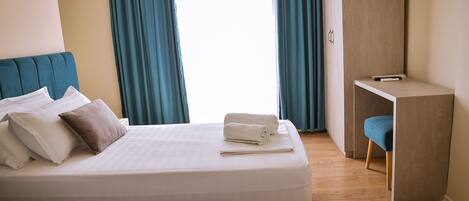 A hotel room with two beds, a desk, and a chair.
