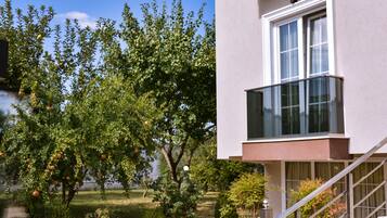 Ein modernes Gebäude mit einem Glasbalkon und einem Garten mit Apfelbäumen.