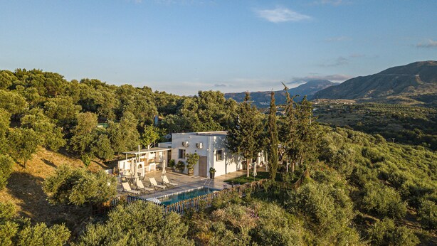 A modern villa with a pool, surrounded by lush greenery and hills in the background. - MariAndry Villa, Secluded Retreat with Pool & HotTub (Episkopi, Rethimno)