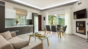 A modern living room with a glass coffee table, a sofa, and a dining area with chairs and a table. - MariAndry Villa, Secluded Retreat with Pool & HotTub (Episkopi, Rethimno)