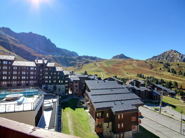 A hotel with multiple buildings, a pool area, and a mountainous backdrop.