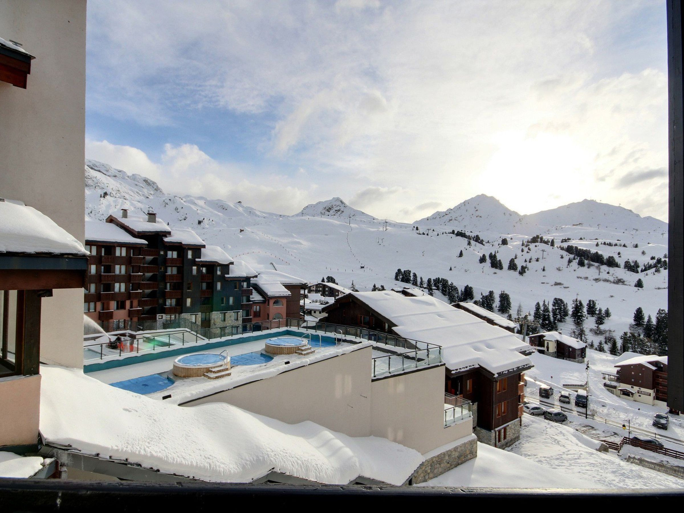 A snow-covered mountain resort with a pool area, ski slopes, and various buildings.
